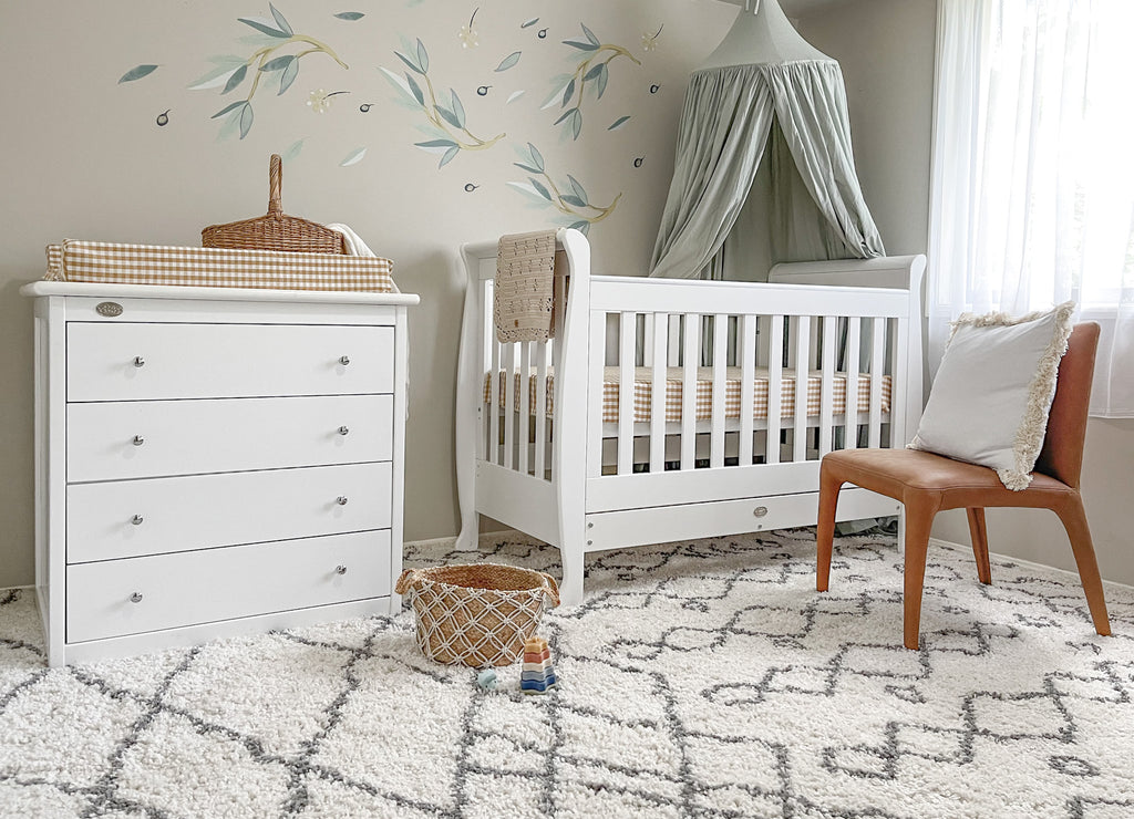 Sleigh cot with 4 drawer chest in a decorated baby room