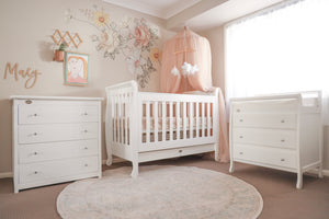 Sleigh cot with chest of drawers and change table in decorated baby room
