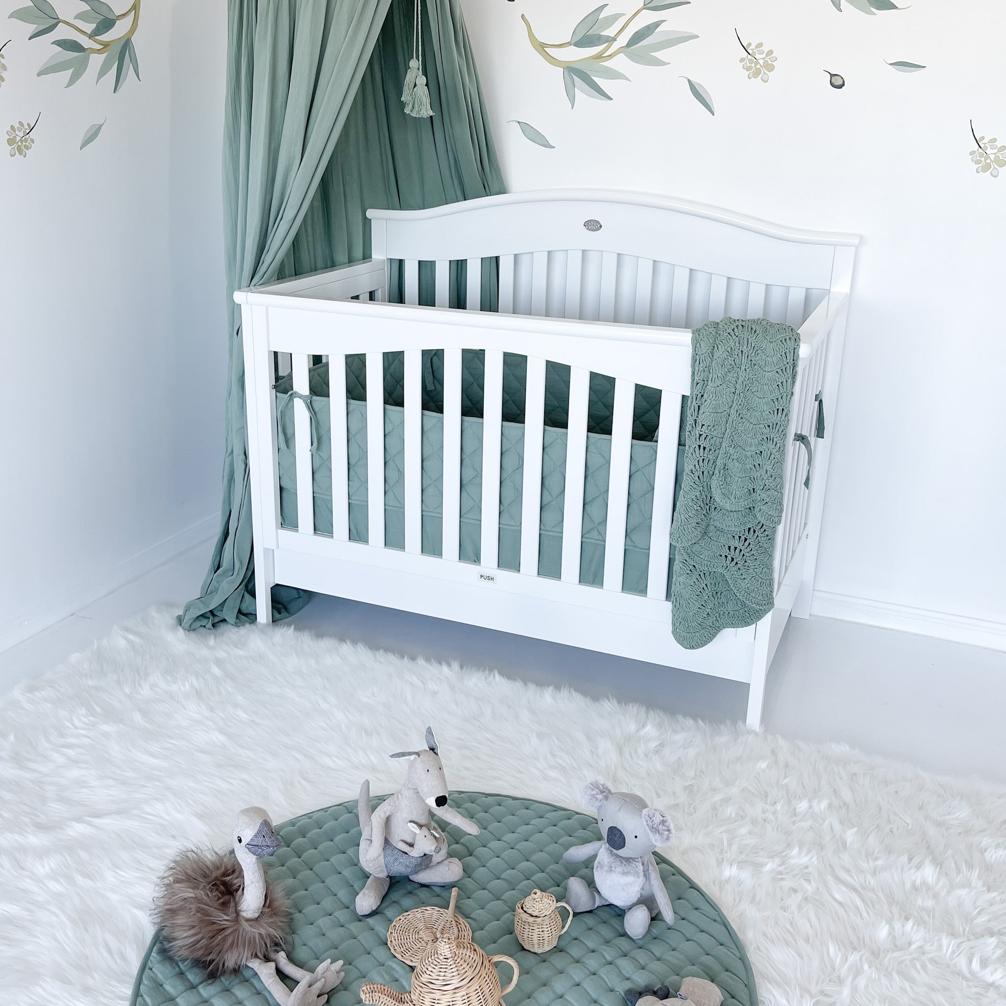 Front side corner view of heritage cot with front rail up and mattress base lowered
